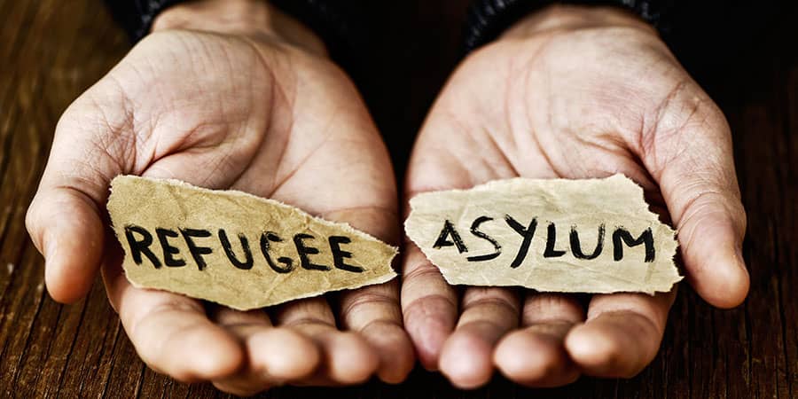A two hands with a paper written refugee on right hand and asylum on its left hand - Ghazi Law Group